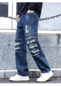 Detail of distressed blue straight-leg jeans with ripped patches and street style denim texture