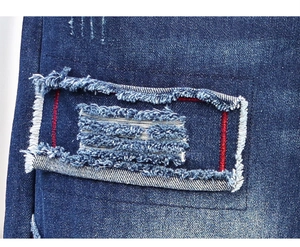 Macro detail of distressed blue denim jeans with patch stitching and red topstitching