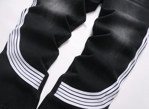 Gros plan sur les rayures blanches latérales et la texture denim délavé du jean noir