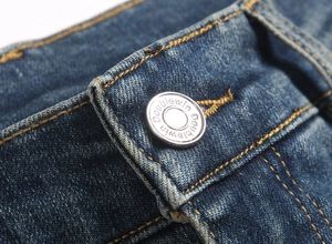 Detailed macro view of retro men's jeans waist with metal button and orange stitching