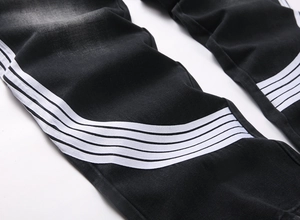 Détail du pantalon large en denim noir avec quatre bandes latérales blanches et effet délavé
