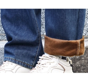 Close-up of distressed denim jeans with warm brown fleece lining and cuffed leg detail