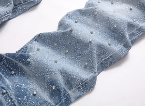 Detailed macro view of light blue flare jeans with silver rhinestones and white paint splatters