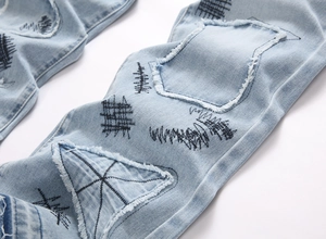 Macro detail of high-quality denim with distressed patchwork and black punk embroidery