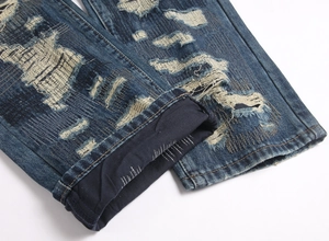 Detailed view of dark blue jeans featuring distressed patches and vintage frayed textures