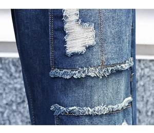 Macro shot of distressed denim fabric with ripped patches and golden yellow stitching