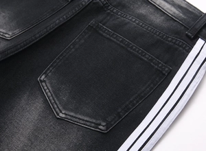 Vue détaillée du denim noir délavé avec les bandes blanches latérales sur la poche