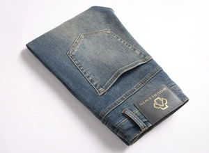 Detailed close-up of dark blue washed denim jeans showing stitching and leather waist tag