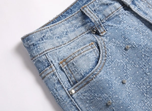 Detail of light blue denim jeans with heavy washing, distressing and rhinestone embellishments