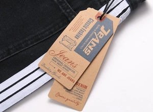 Détail macro d'un jean en denim noir avec bandes latérales blanches et étiquettes vintage
