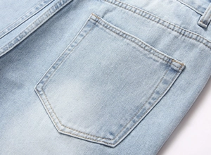 Detailed macro view of light blue denim fabric with double-stitched back pocket textures