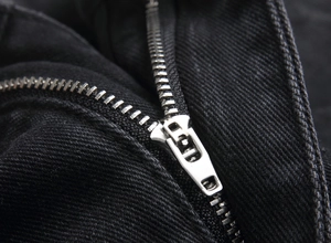 Gros plan sur la braguette à fermeture éclair argentée du pantalon en jean noir denim