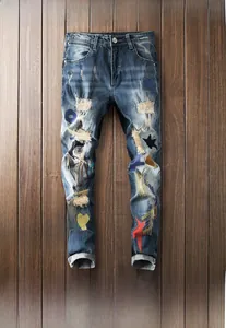 Detailed close-up of distressed dark blue denim with star embroidery and ripped patches