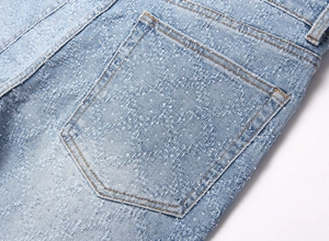 Detail of light blue denim jeans with sparkling rhinestone pattern and distressed texture