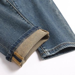 Close-up of men's slim stretch blue denim jeans cuff with contrast stitching detail