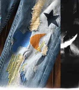 Macro detail of men's distressed jeans with moon, star embroidery and colorful patches