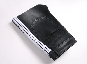 Détail d'un jean denim large avec bandes blanches latérales et texture délavée naturelle