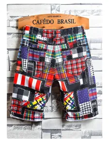 Detail view showing the colorful patchwork plaid pattern and cotton fabric texture of the shorts