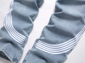 Vue détaillée du jean bleu clair avec quatre bandes blanches sportives sur le bas de jambe