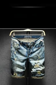 Detail of light blue distressed denim shorts with ripped patches and washed texture