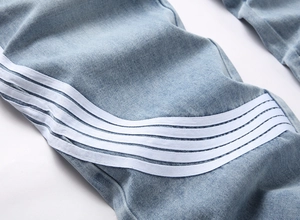 Gros plan du denim bleu clair avec quatre bandes blanches et coutures détaillées du jean