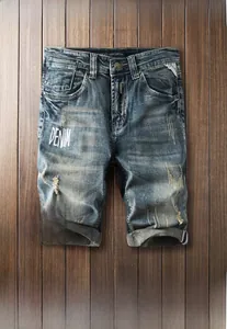 Détail du short en jean bleu délavé avec déchirures et impression blanche sur tissu