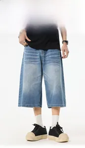 Detail shot of men's wide-leg light blue washed denim shorts on a model with white background