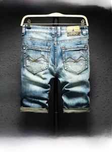 Detail view of light blue distressed denim shorts with back pocket wavy embroidery and leather patch
