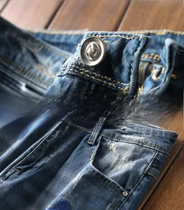 Detail of vintage copper button and yellow stitching on dark blue washed denim jeans