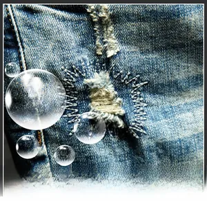 Macro detail of blue denim shorts showing frayed distressed holes and zigzag stitch repairs