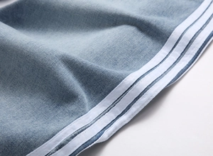 Gros plan du denim bleu clair avec trois bandes blanches latérales et coutures précises