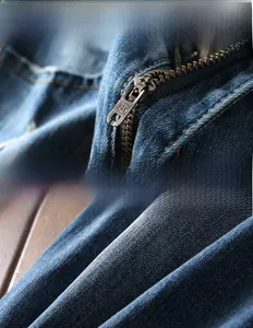 Detailed macro view of copper zipper and distressed edge on blue denim jeans