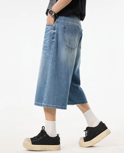 Detail of loose fit wide-leg denim shorts in washed blue with street style silhouette
