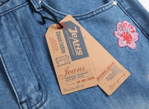 Gros plan d'étiquettes marron sur un jean bleu avec des détails de broderie florale