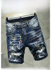 Detail of distressed denim shorts featuring colorful paint splatter and frayed holes