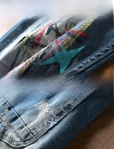 Detail of colorful star embroidery and distressed stitching on dark blue denim jeans