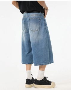 Detail view of the back pockets and stitching on men's loose washed blue denim shorts