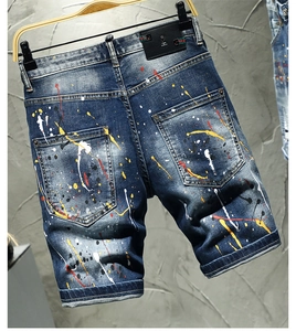 Macro detail of hand-painted colorful splatters and stripe patch on blue denim shorts