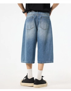 Detail shot of men's loose washed blue denim cropped pants showing back pockets and fit