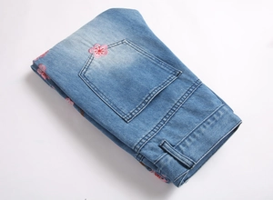 Détail du jean délavé bleu clair avec broderie florale rose sur la poche arrière