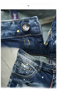 Detail of blue distressed denim shorts with paint splatters, metal button, and pockets