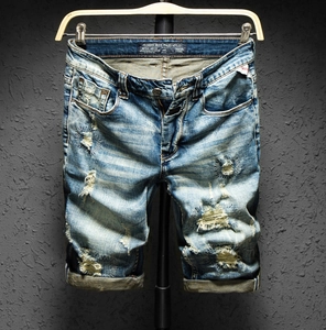 Detailed view of men's vintage light blue distressed denim shorts with frayed ripped holes