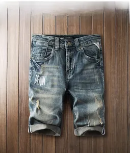 Détail de short en jean vintage bleu avec déchirures et lettrage blanc imprimé denim