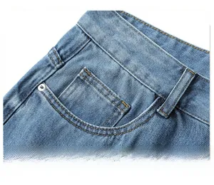 Detail of light blue denim jeans showing the side pocket with metal rivets and stitching