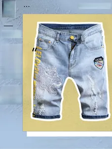 Détail de la broderie tête de tigre et des déchirures sur ce short en denim