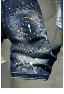Detail of blue denim shorts featuring artistic paint splatters and back pocket stitching