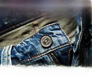 Detailed macro view of retro men's denim shorts with classic copper button and metal zipper