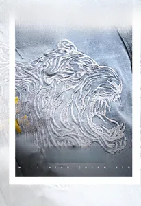 Détail de la broderie tête de tigre blanche sur short en jean bleu clair et lettrage doré