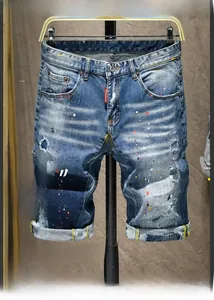 Détail du short en jean usé avec des taches de peinture colorées et une étiquette rouge