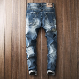 Vintage wash blue distressed slim denim pants with moon embroidery on dark wood background
